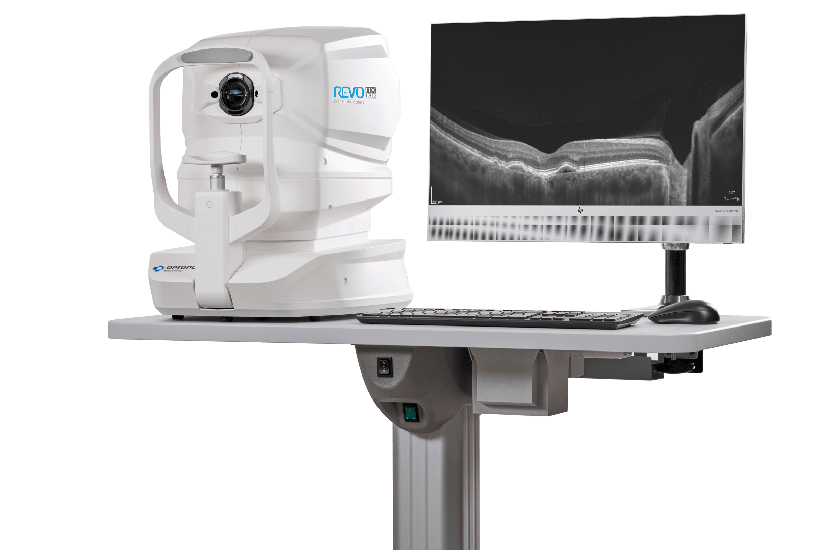 Ein medizinisches Bildgebungsgerät mit der Bezeichnung REVO liegt auf einem Tisch neben einem Monitor, auf dem ein Schwarz-Weiß-Querschnittsbild, wahrscheinlich von einem Augenscan, angezeigt wird. Eine Tastatur und eine Maus befinden sich ebenfalls auf dem Tisch.