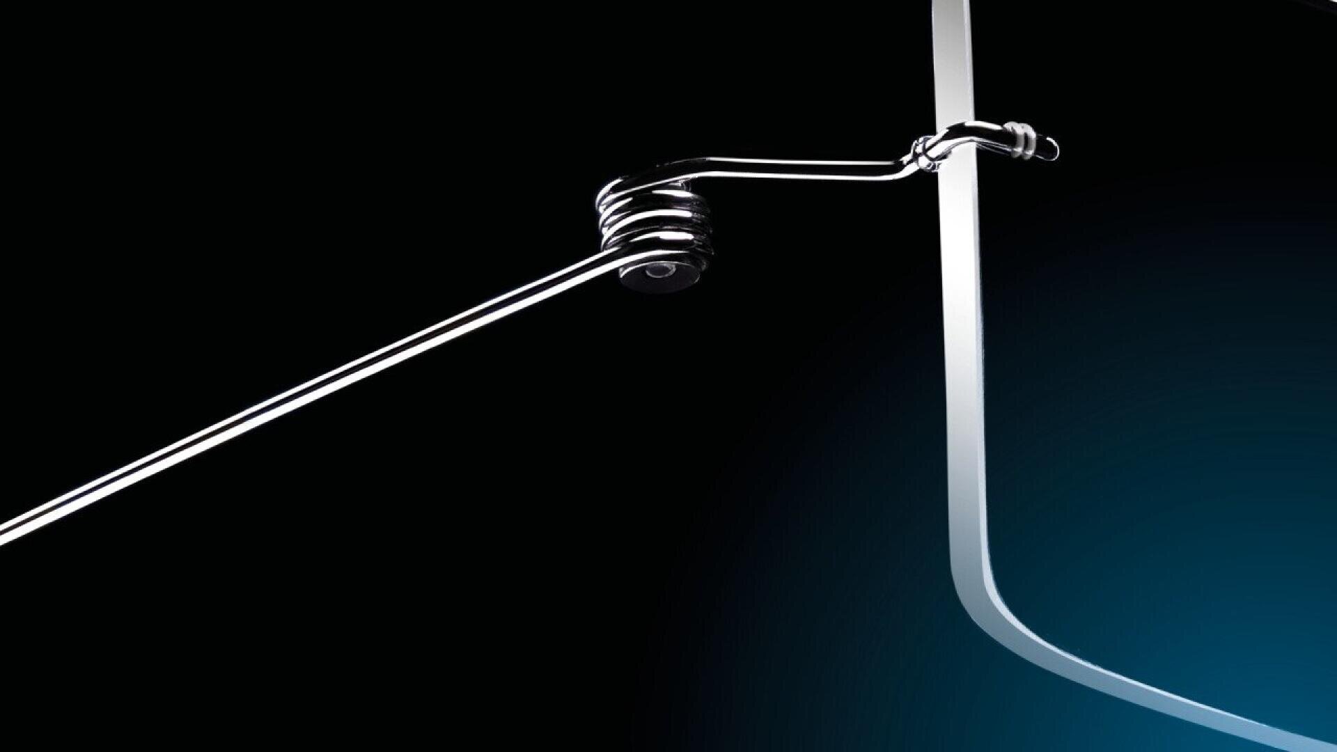 Close-up of a sleek, metallic eyeglass frame against a black and blue gradient background, highlighting the hinge and temple arm with a minimalist, modern design.