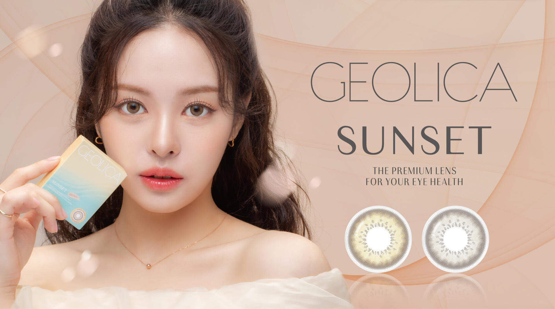 A woman with long dark hair is holding a box of Geolica Sunset contact lenses. Two contact lenses are pictured next to her. In the background is the text GEOLICA SUNSET, the premium lens for your eye health.