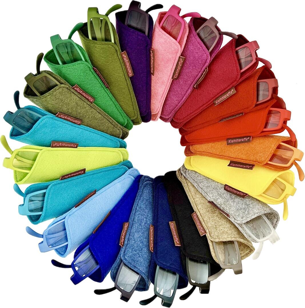 Eine kreisförmige Anordnung von bunten Brillenetuis in einem Regenbogenmuster mit Farbverlauf, wobei jedes Etui eine Brille enthält. Die Farben umfassen Grün-, Blau-, Lila-, Rosa-, Rot-, Orange-, Gelb- und Beigetöne.