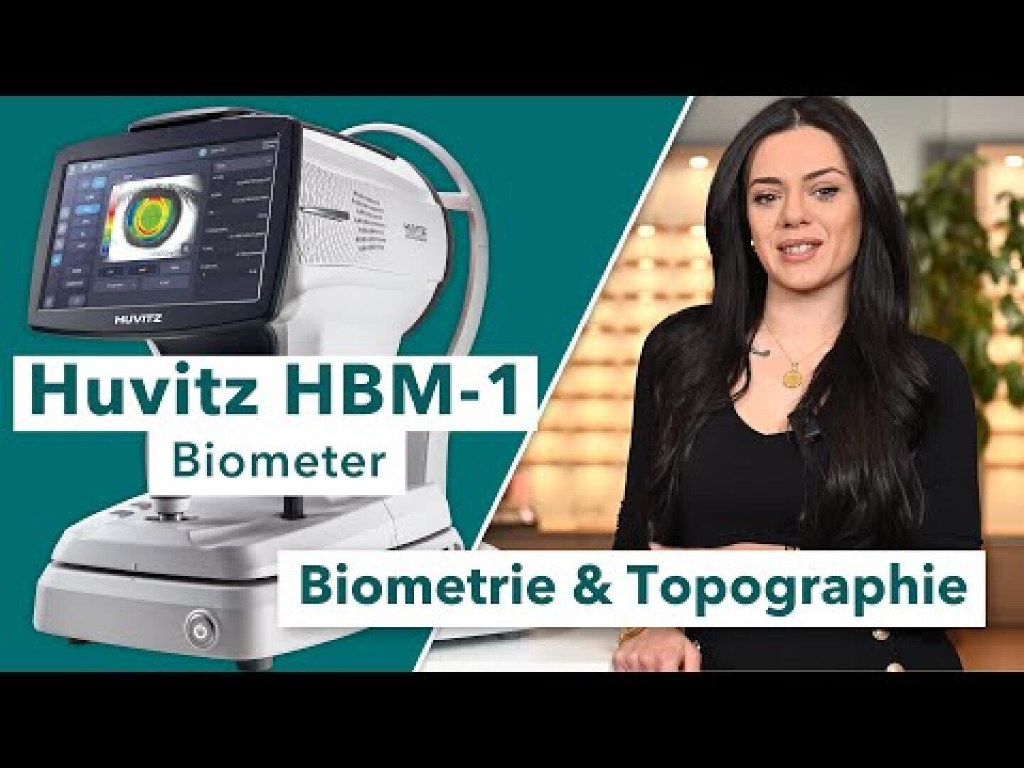 Eine Frau steht neben einem weißen Huivtz HBM-1 Biometer-Gerät. Der Text auf dem Bild lautet: Huvitz HBM-1 Biometer und Biometrie & Topographie. Der Hintergrund ist blaugrün und ein Innenraum ist zu sehen.