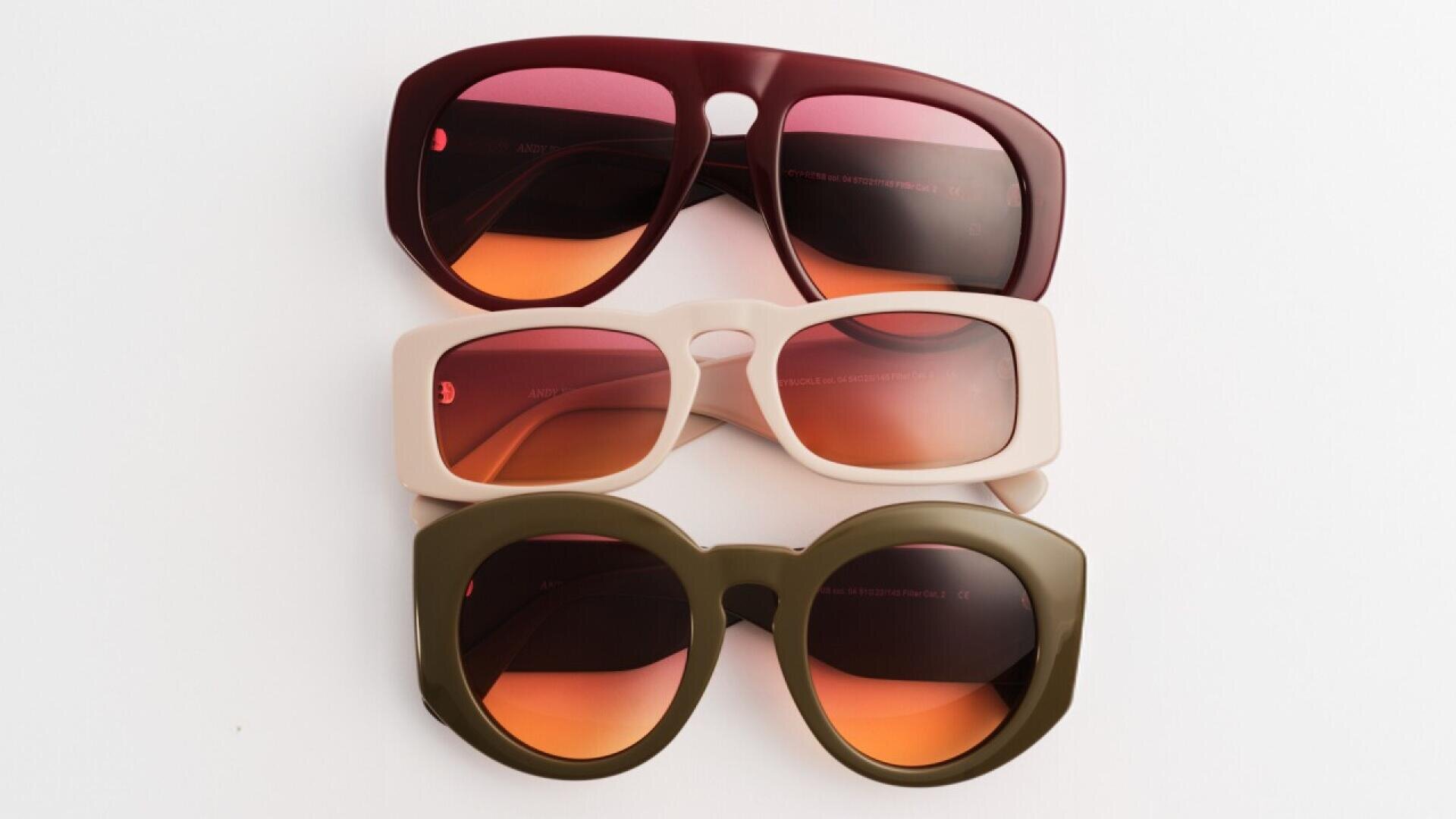 Three pairs of sunglasses with tinted pink lenses arranged vertically on a white background: one with a burgundy frame, one with a cream frame, and one with a green round frame.