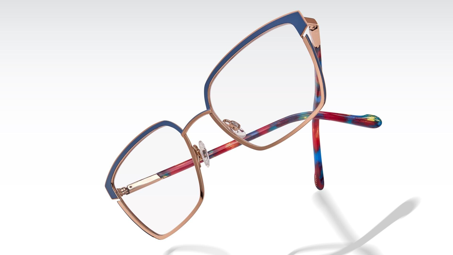 Eine stilvolle Brille mit goldenen Metallrändern, blauen Akzenten auf der Oberseite und mehrfarbigen roten, blauen und grünen Bügeln auf einem weißen Hintergrund mit einem weichen Schatten.