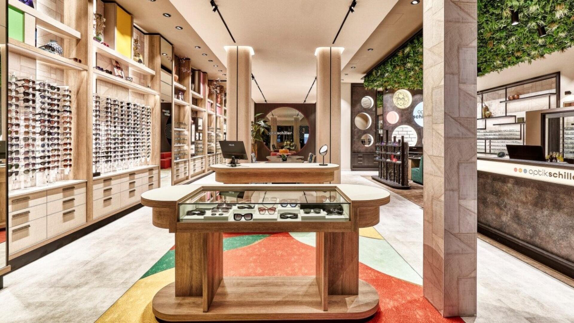 A modern eyewear store interior featuring glasses on display racks, a central wooden display counter with sunglasses, a colorful floor design, and bright, stylish lighting.