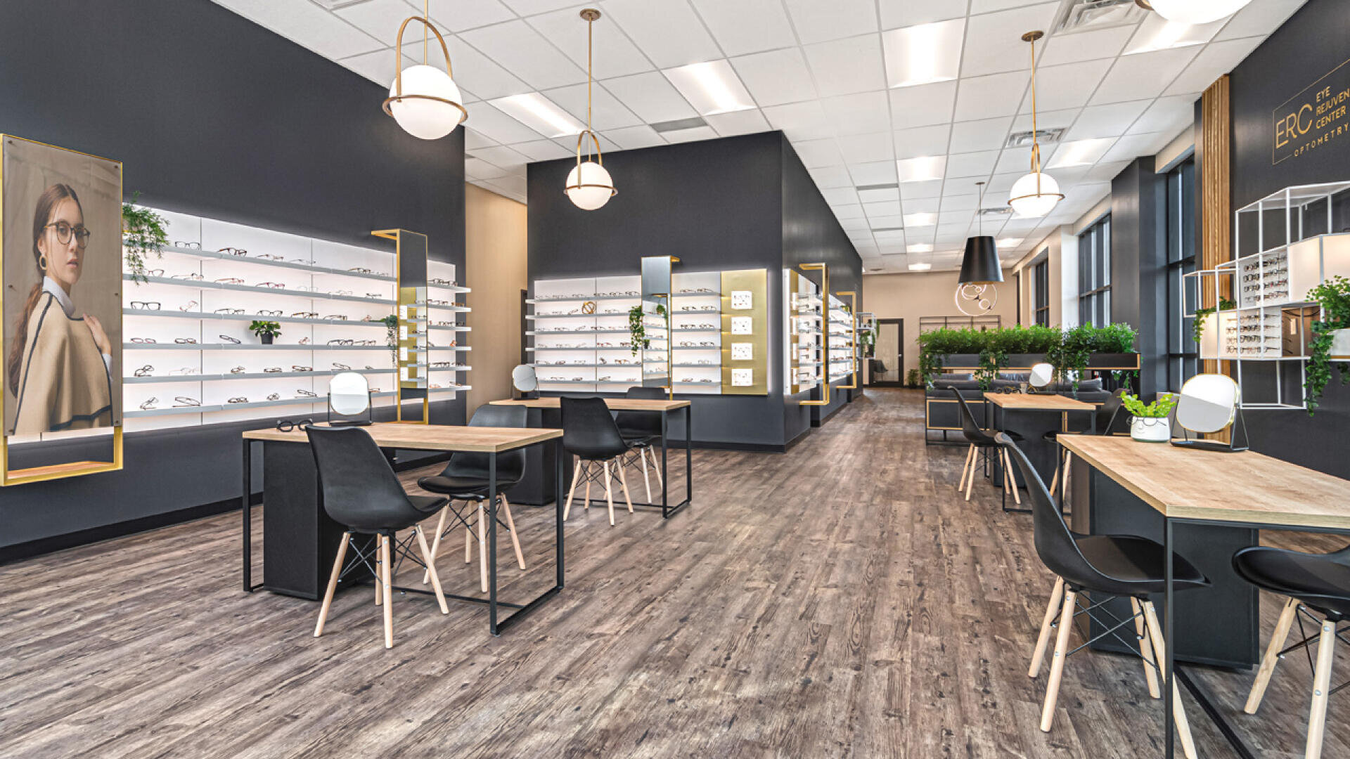 Modern optometry office with large windows, sleek black and wood furniture, display shelves of eyeglasses, potted plants, pendant lights, and a portrait of a woman wearing glasses on the wall.