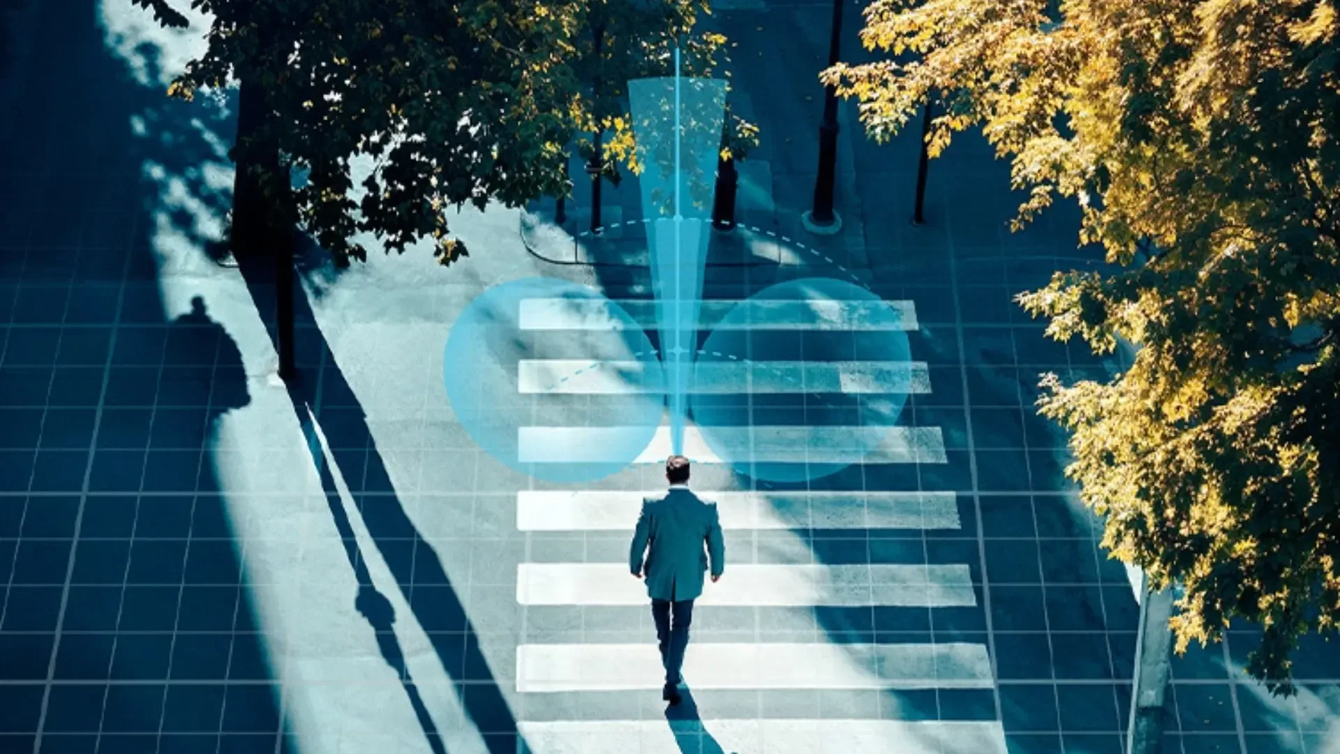 Eine Person in Geschäftskleidung überquert an einem Zebrastreifen eine von Bäumen gesäumte Straße. Über ihrem Kopf ist eine blaue digitale Einblendung zu sehen, die ein Konzept von Technologie, Navigation oder Konnektivität suggeriert.