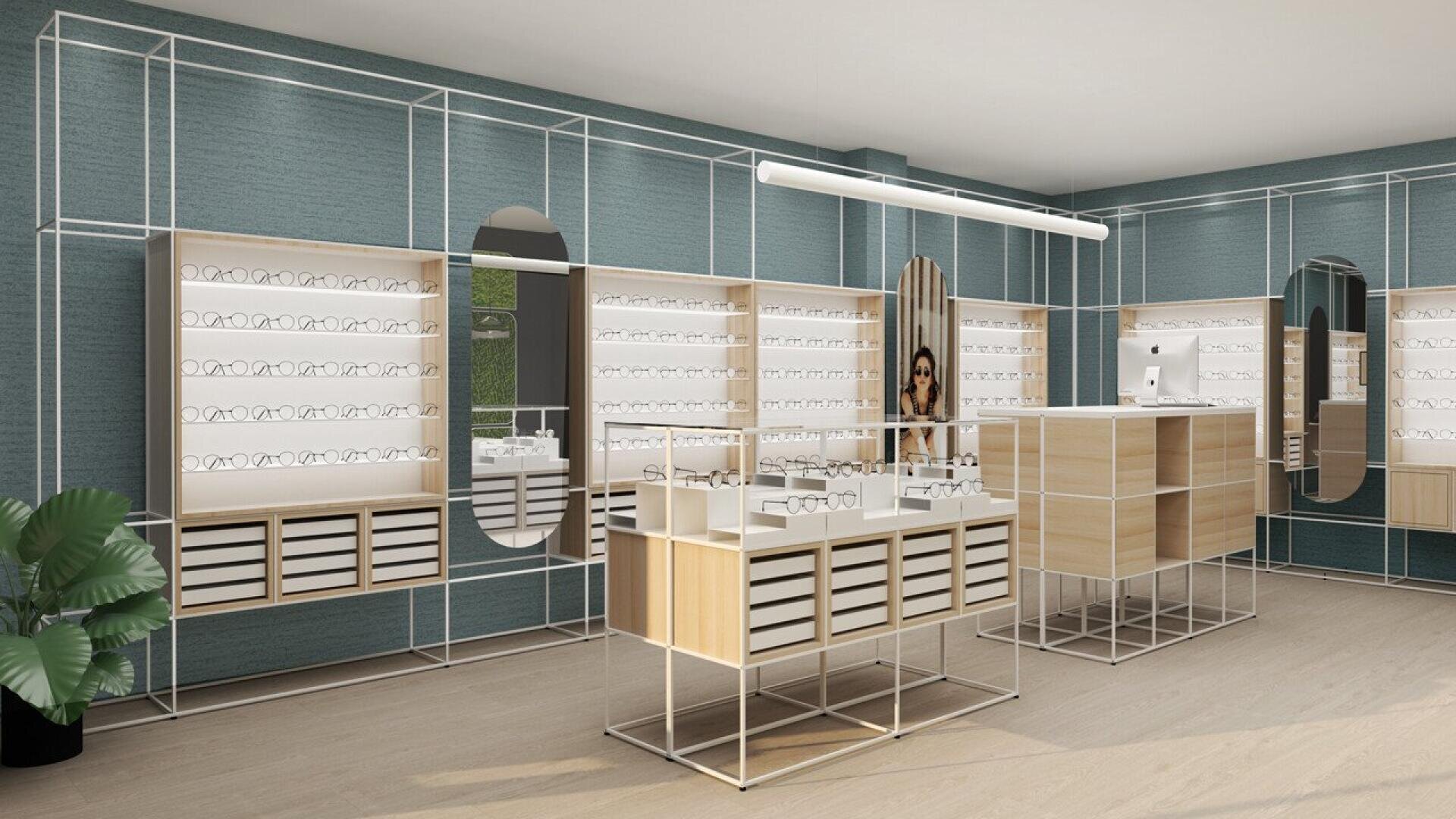 Modern eyewear store interior with minimalist shelves holding glasses, large mirrors, wooden display tables, a counter with a computer, green accent walls, and a potted plant in the corner.
