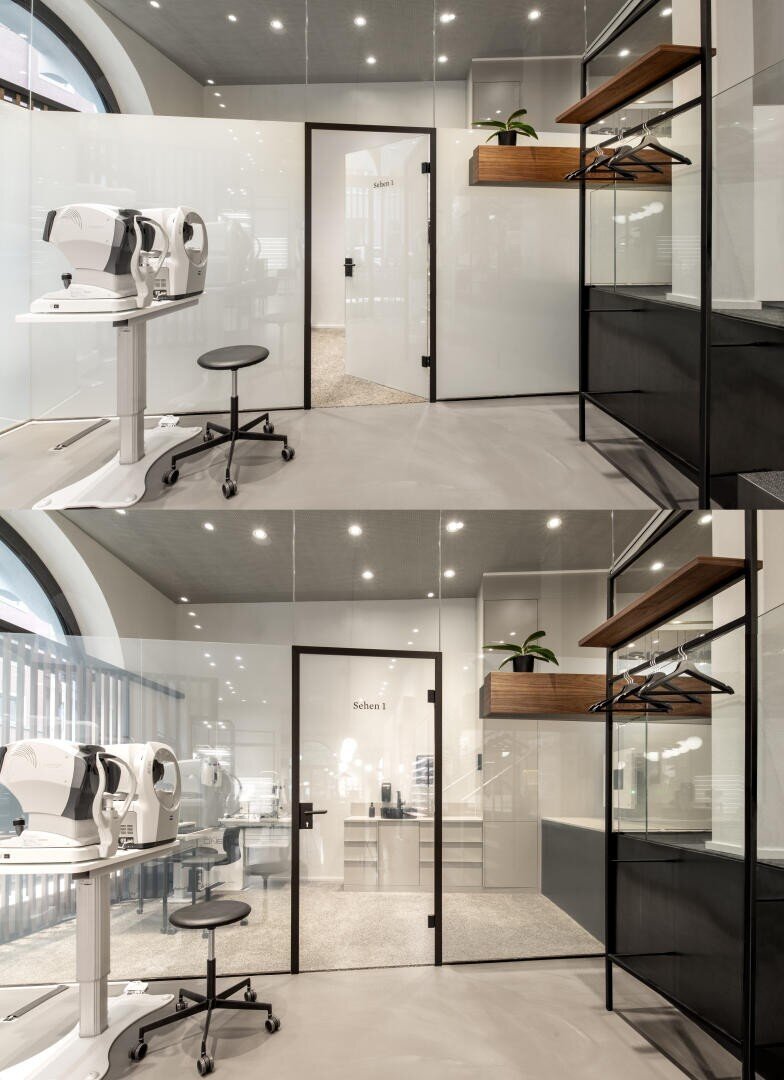 Moderne, minimalistische Augenarztpraxis mit Augenuntersuchungsgeräten, einem schwarzen Hocker, Glaswänden, Regalen mit einer Pflanze, Kleiderbügeln und einer Tür mit der Aufschrift "Schritt 1". Das untere Bild zeigt denselben Raum aus einem etwas niedrigeren Winkel.