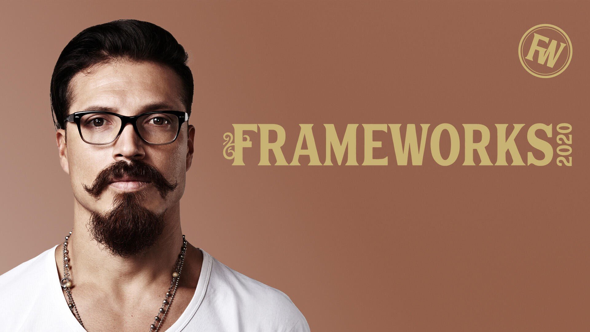 A man with dark hair, glasses, a styled moustache and beard stands in front of a brown background. The word FRAMEWORKS 2020 and a round FW logo appear next to him in large, golden letters.