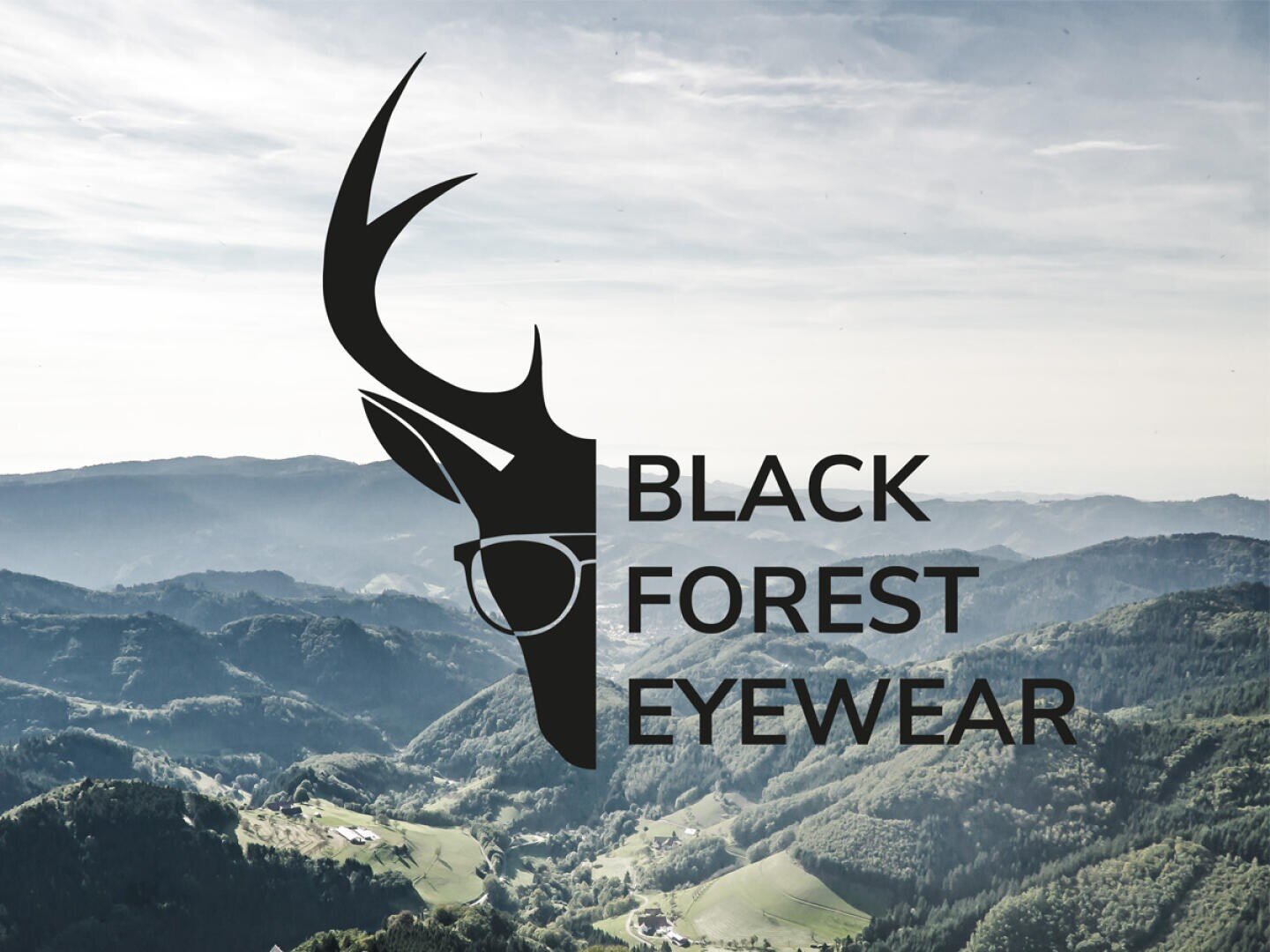Ein Logo mit einem schwarzen Hirschkopf, der eine Brille trägt, und dem Text BLACK FOREST EYEWEAR liegt über einer malerischen, bergigen Waldlandschaft mit Hügeln und Dörfern darunter.