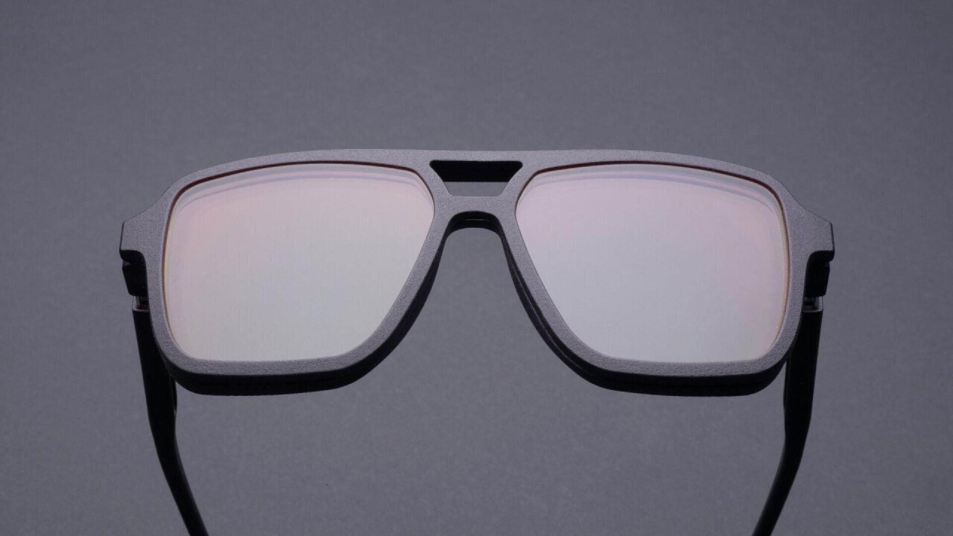 A pair of black, rectangular sunglasses with slightly reflective lenses, displayed against a plain gray background.