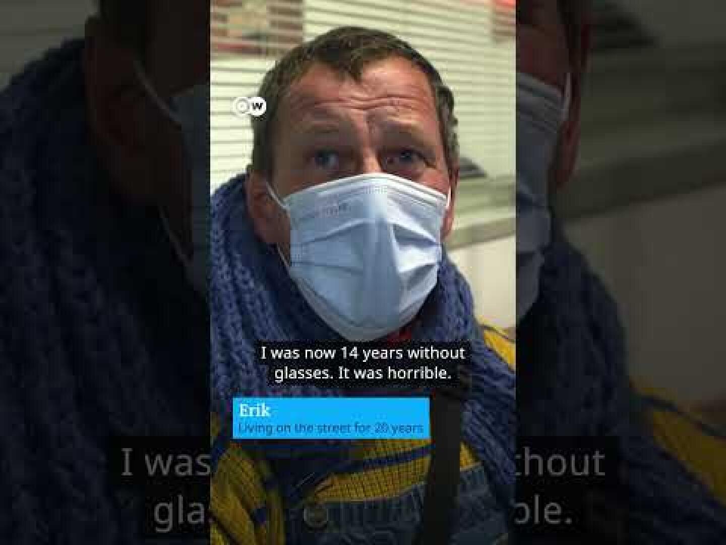 A man wearing a white medical mask, a blue scarf and a yellow jacket looks into the camera. The text on the picture reads: "I've been without glasses for 14 years now. It was terrible" and "Erik, who has lived on the street for 20 years".