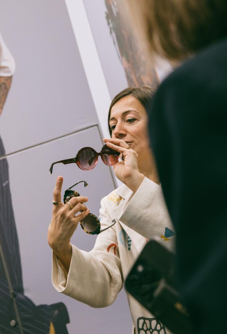 Eine Frau mit Sonnenbrille vor einem Spiegel.