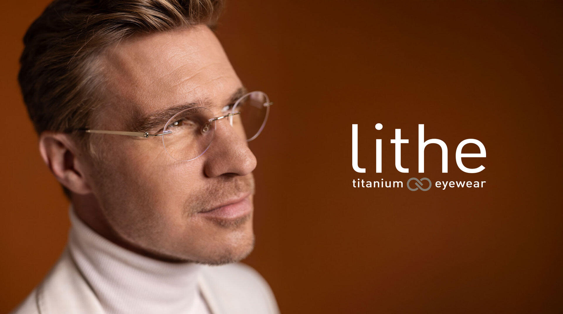 Ein Mann mit einer dünnen, randlosen Brille und einem weißen Rollkragenpullover blickt vor einem braunen Hintergrund nach oben. Neben ihm erscheint der Text lithe titanium eyewear.