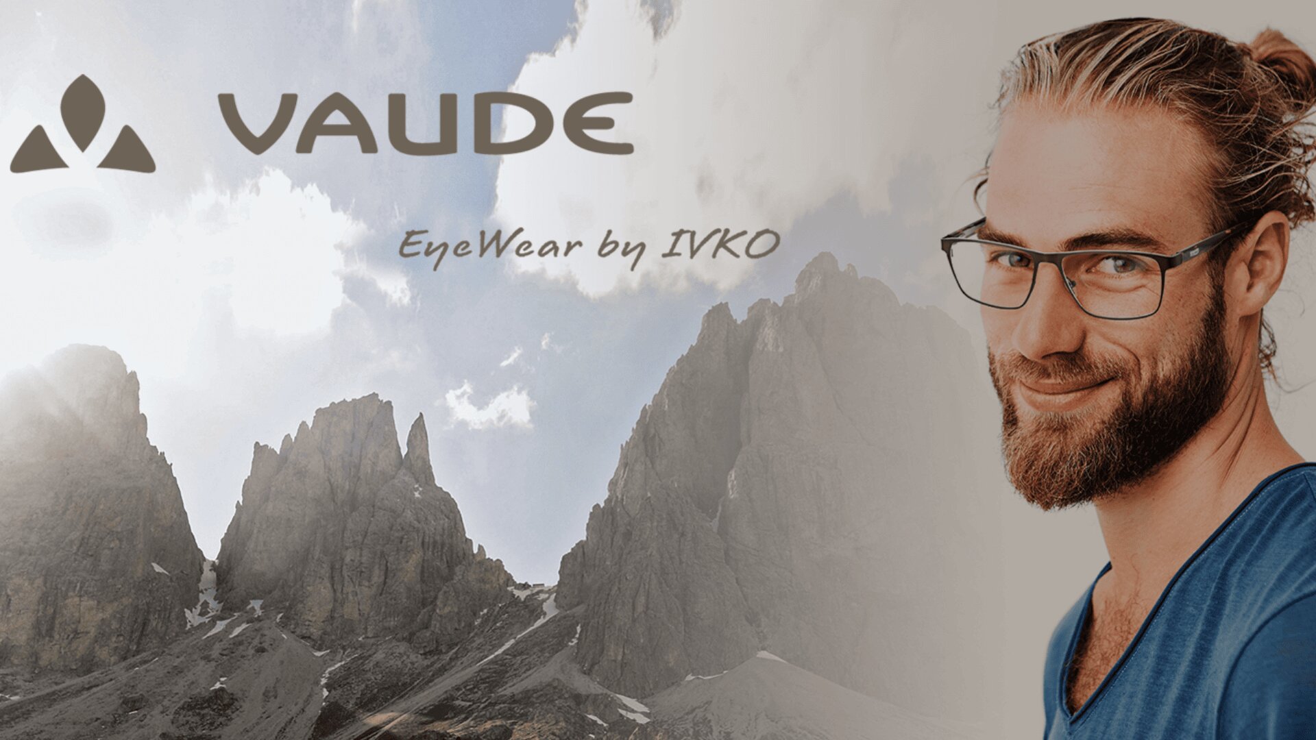 Ein lächelnder Mann mit Brille und Bart steht vor einer Berglandschaft mit zerklüfteten Gipfeln. Der Text lautet VAUDE und EyeWear by IVKO in stilvollen Schriftarten.