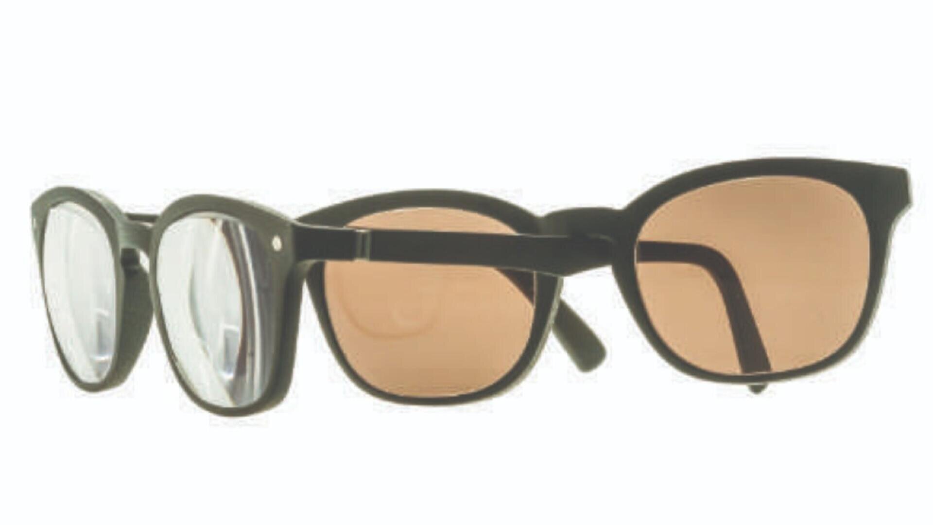 A pair of black eyeglasses with a detachable clip-on sunglass lens, shown partially attached over the clear prescription lenses.