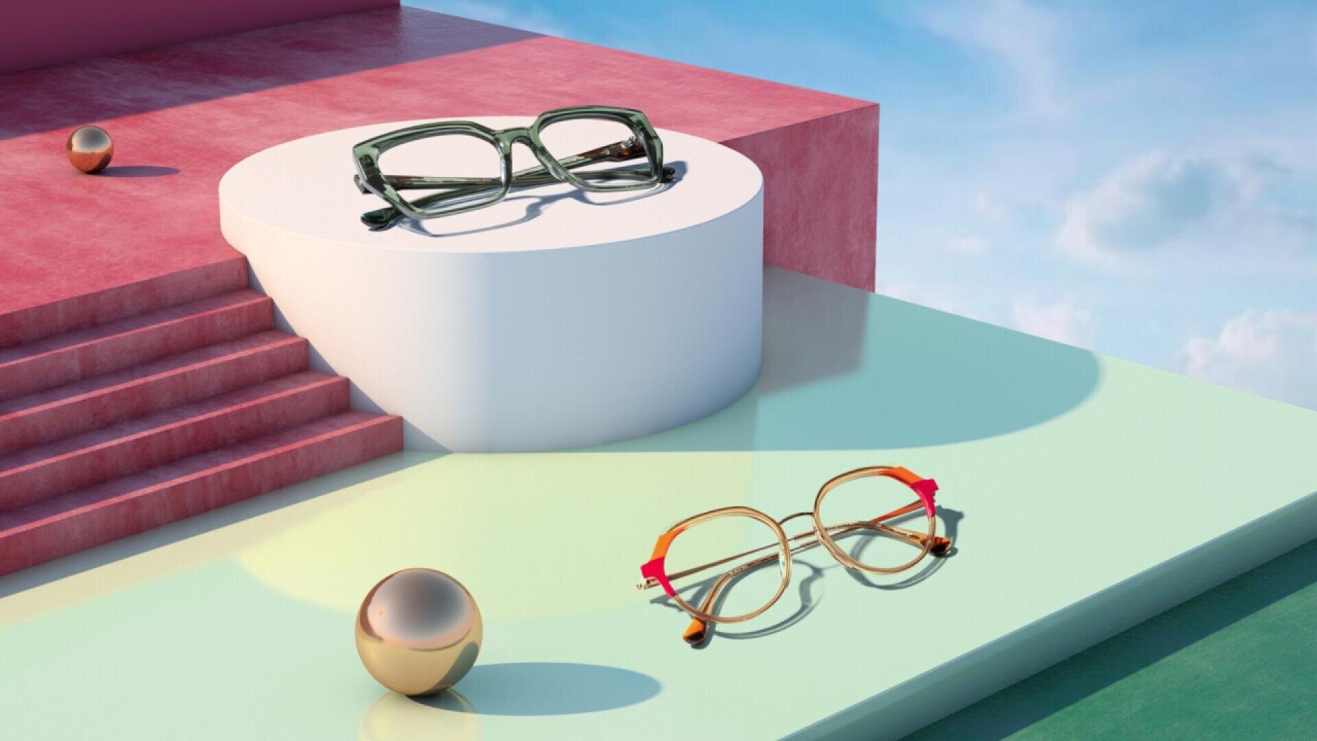 Two pairs of eyeglasses are displayed on geometric platforms with pastel colors. One pair is square and green on a white pedestal; the other is round and gold with red arms on a mint-green surface. Metallic spheres complete the scene.