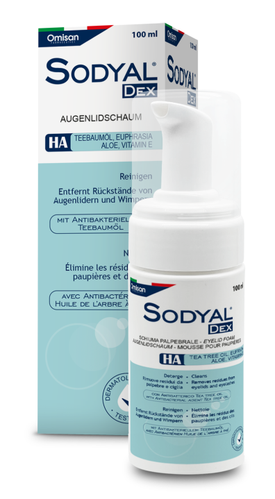 Eine weiß-blaue Flasche Sodyal DEX Augenlidschaum steht vor der dazugehörigen Schachtel. Die Verpackung enthält einen Text auf Deutsch und Französisch, der Inhaltsstoffe wie Teebaumöl, Aloe und Vitamin E hervorhebt.