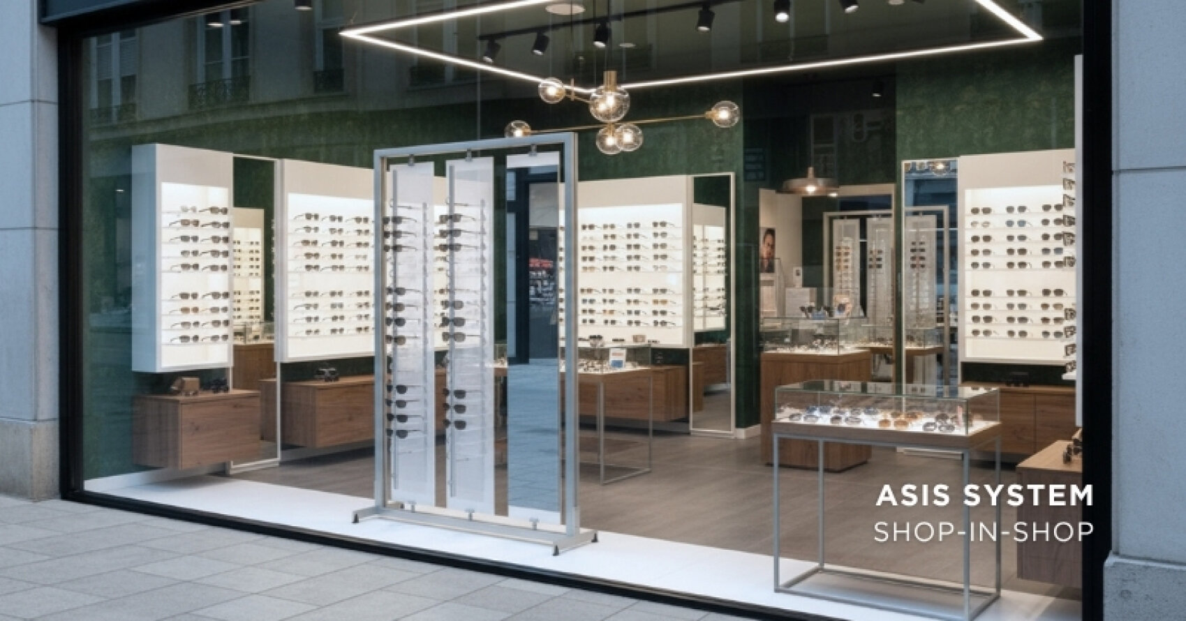 A modern eyewear store with large glass windows, showcases full of glasses and sunglasses, bright lighting and elegant wooden furniture. In the bottom right-hand corner it says "ASIS SYSTEM SHOP-IN-SHOP".
